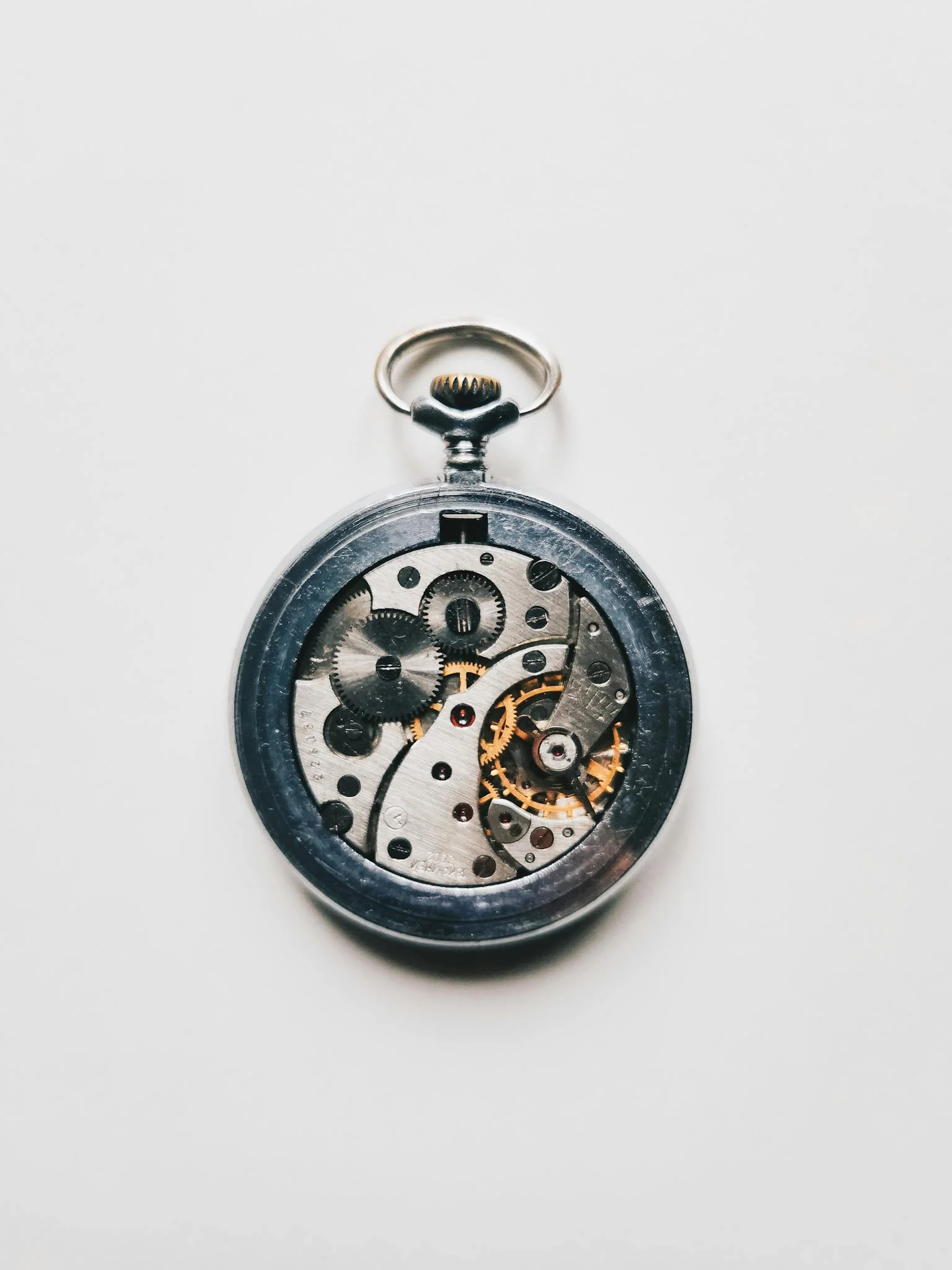 Close-up of a vintage pocket watch's intricate mechanism against a clean white background.