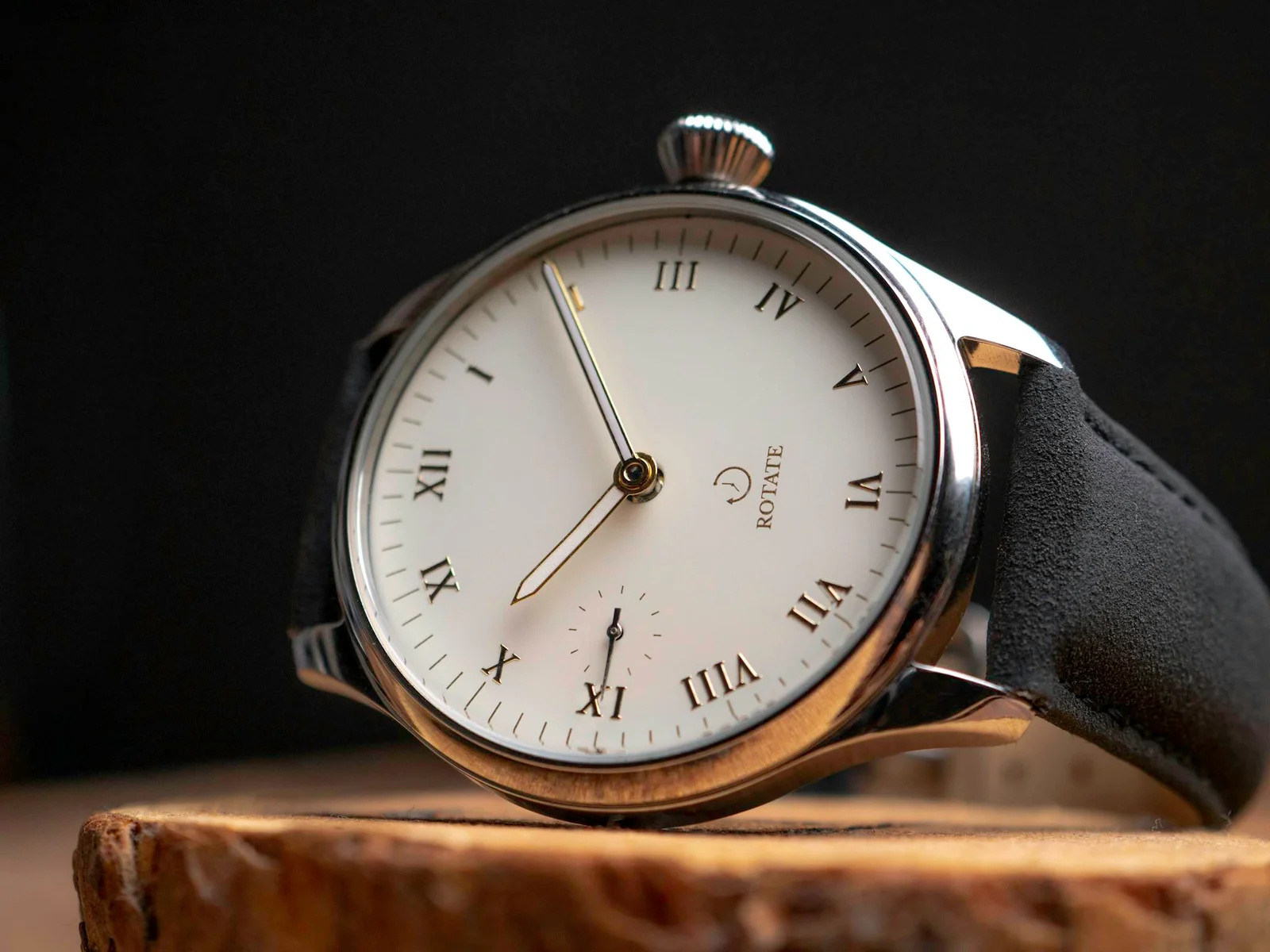 Sophisticated close-up of a classic wristwatch on a wooden surface with Roman numerals.